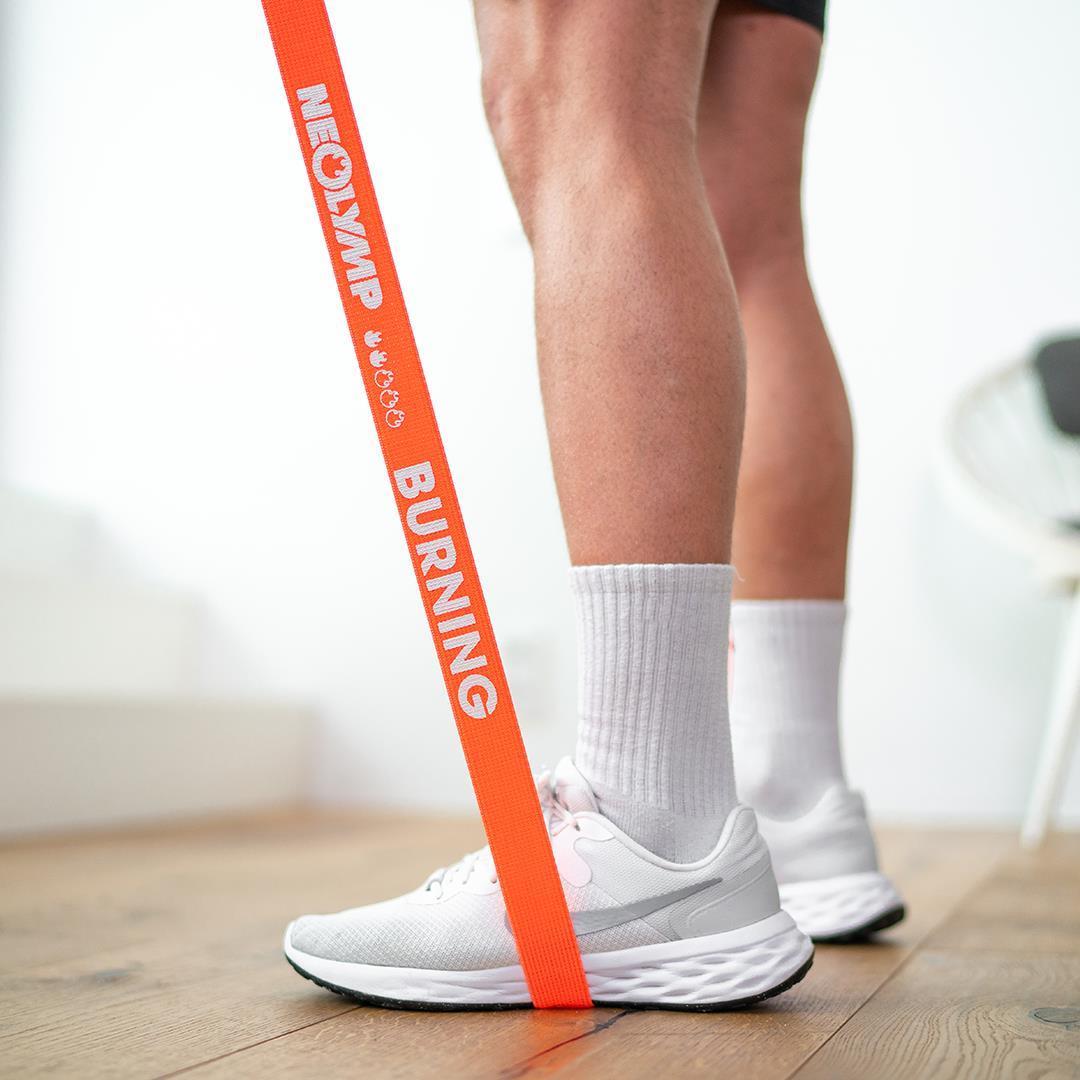 Mann steht auf einem Stretchband mit der Widerstandsstufe 2 und zieht es nach oben