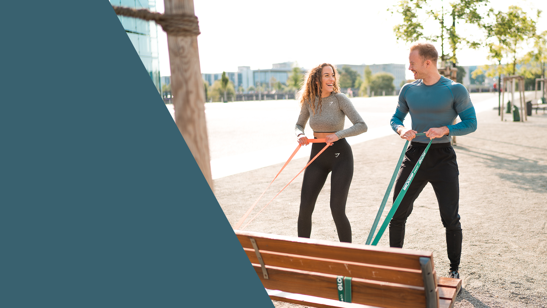 Mann und Frau trainieren gemeinsam im Freien mit Neolymp Widerstandsbändern. Die beiden lächeln, während sie Übungen an einer Parkbank durchführen. Ideal für Outdoor-Workouts.