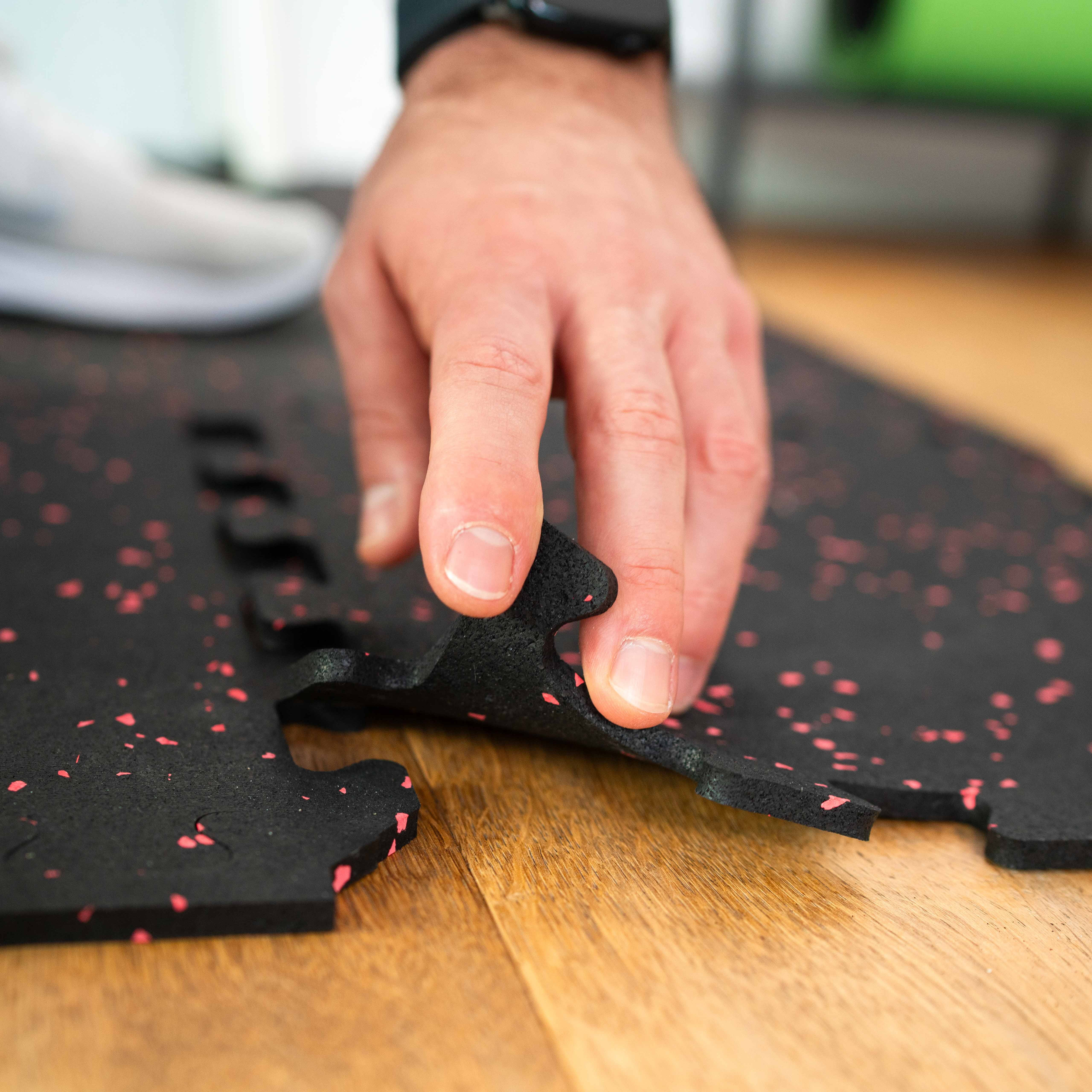 Eine Person legt ein Stück Puzzlematte auf eine Puzzlematte und verbindet die Teile.